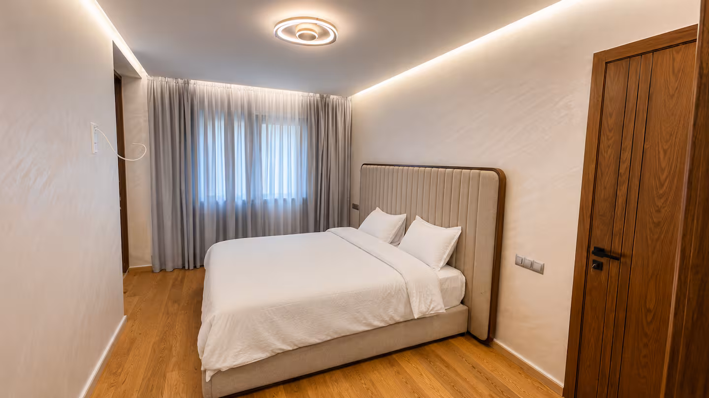 Primary bedroom with an upholstered headboard at a Nūr-managed apartment